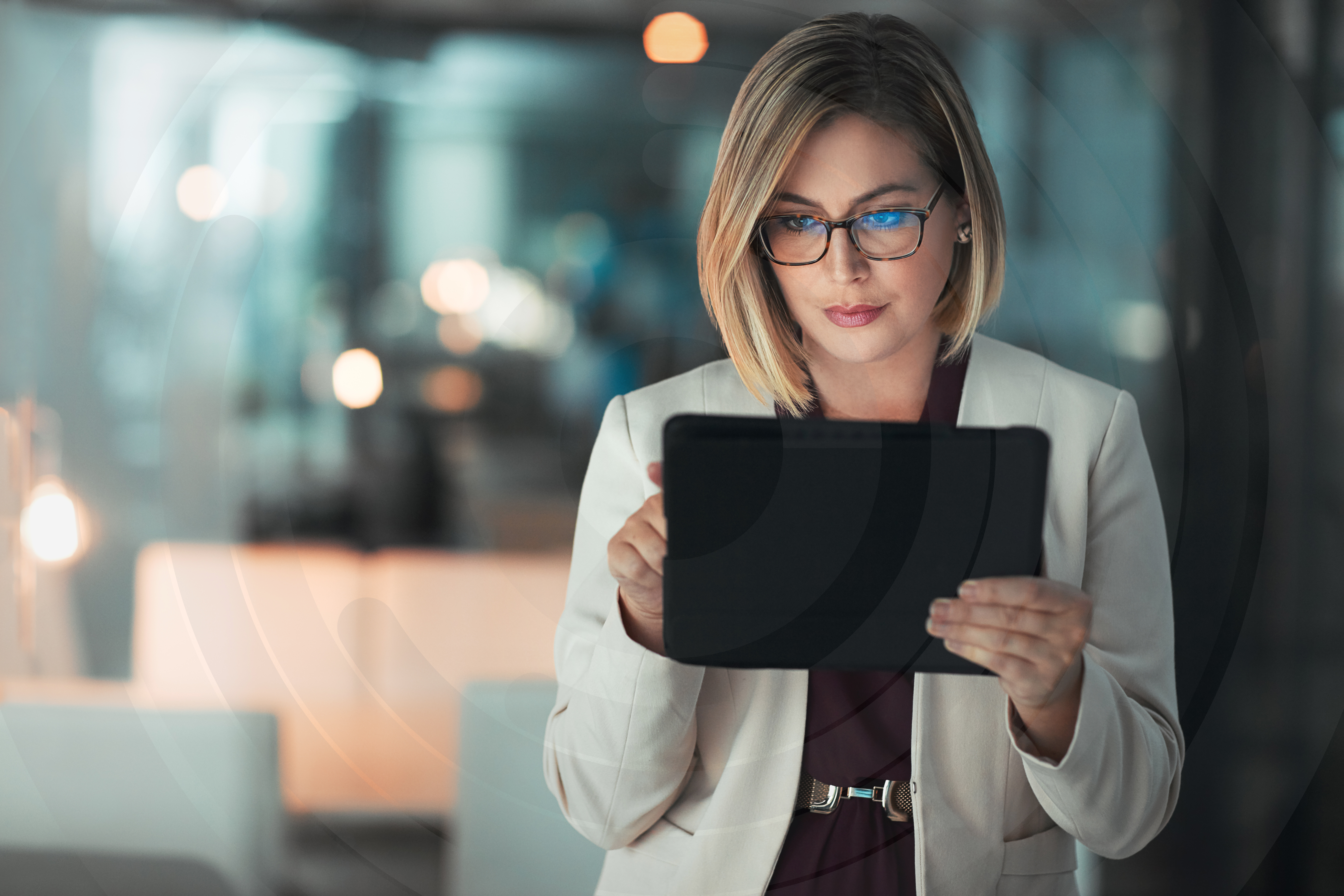 White woman with blonde hair and glasses working on a tablet